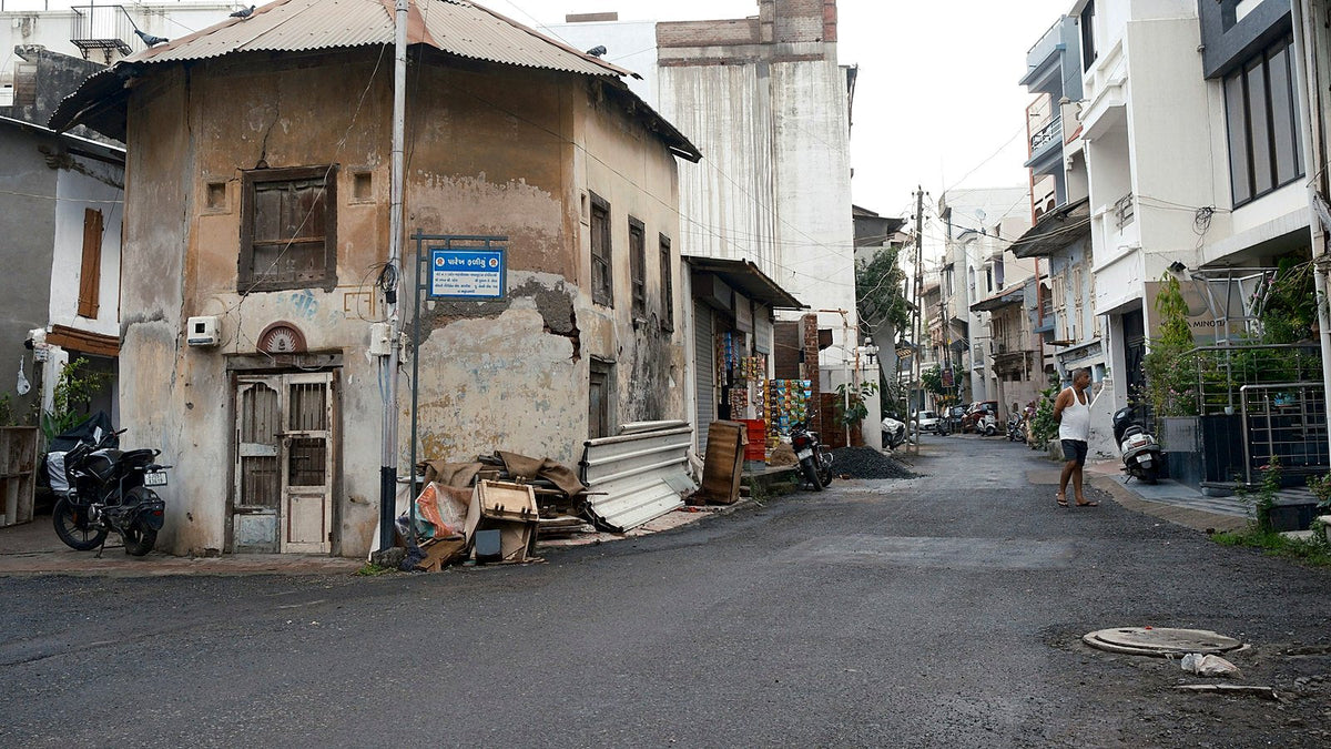 A motorcycle parked outside an old house on a quiet lane in an Indian town