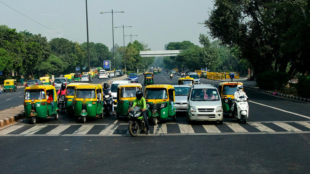 Auto-rickshaws, cars and bikes waiting at a stop line on a Delhi road