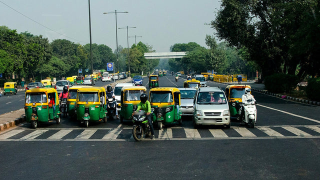 Auto-rickshaws, cars and bikes waiting at a stop line on a Delhi road