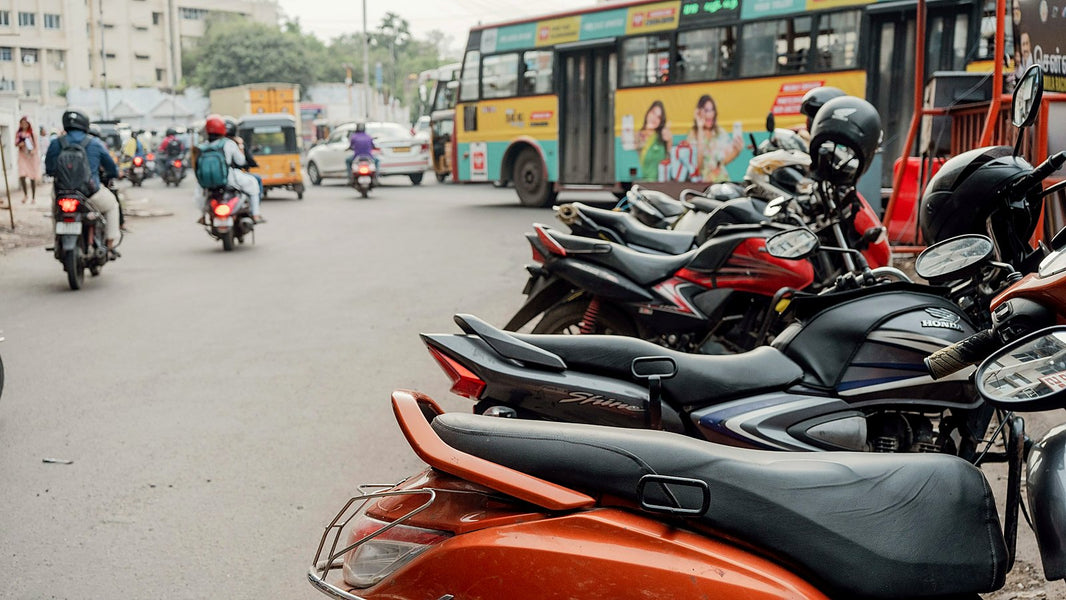A row of motorcycles and scooters parked along a busy Indian street