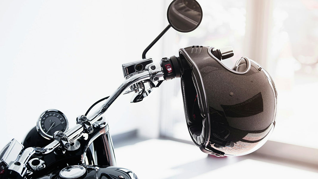 A helmet hanging from a motorcycle handlebar instead of being worn